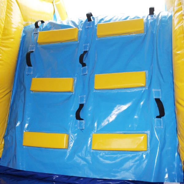 Closeup of a bouncy castle climbing wall leading to the slide. Featuring yellow steps and black handles.